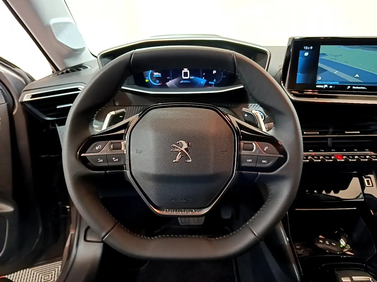 Volant cuir noir avec logo Peugeot au centre, tableau de bord numérique et écran tactile à droite dans l'habitacle d'une 208 2022.