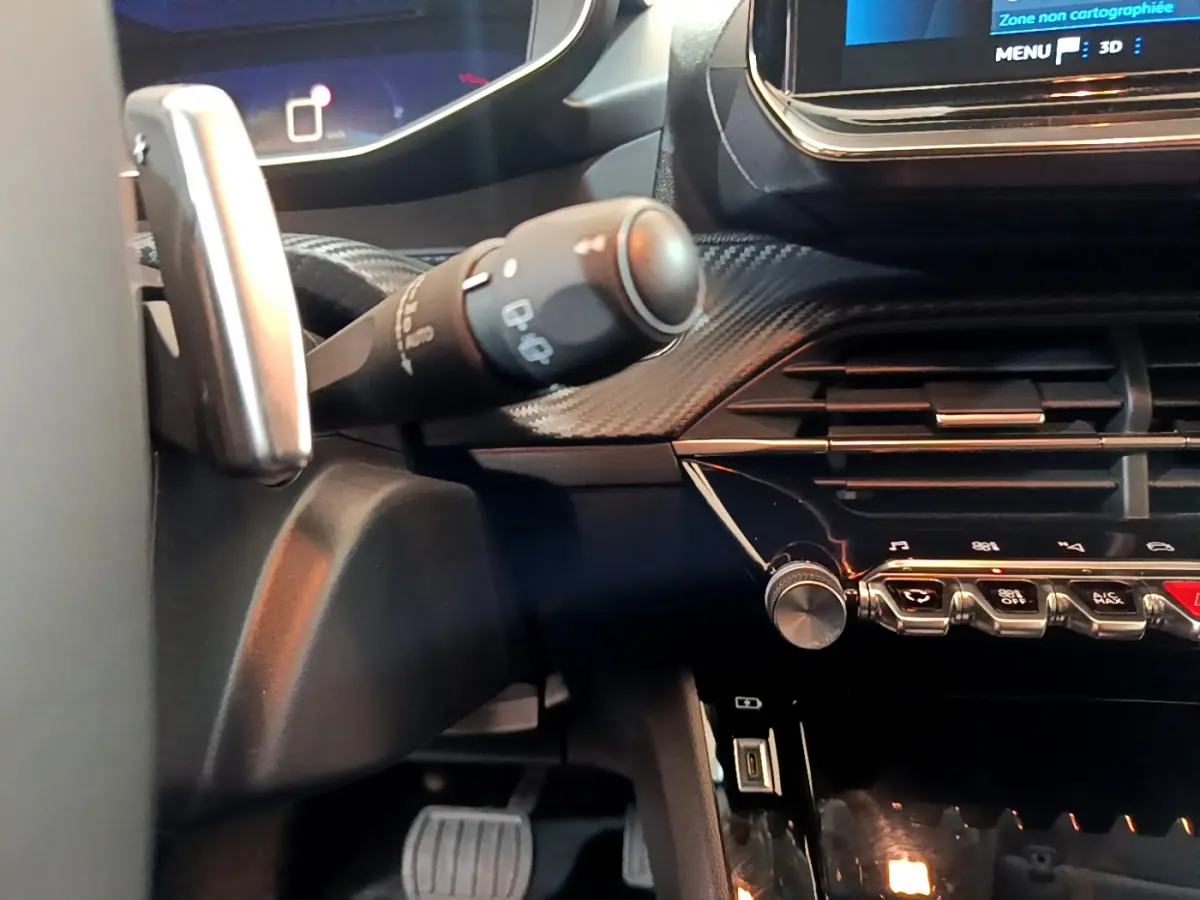 Gros plan sur la commande d'essuie-glace et la console centrale noire du tableau de bord du Peugeot 208 gris foncé.