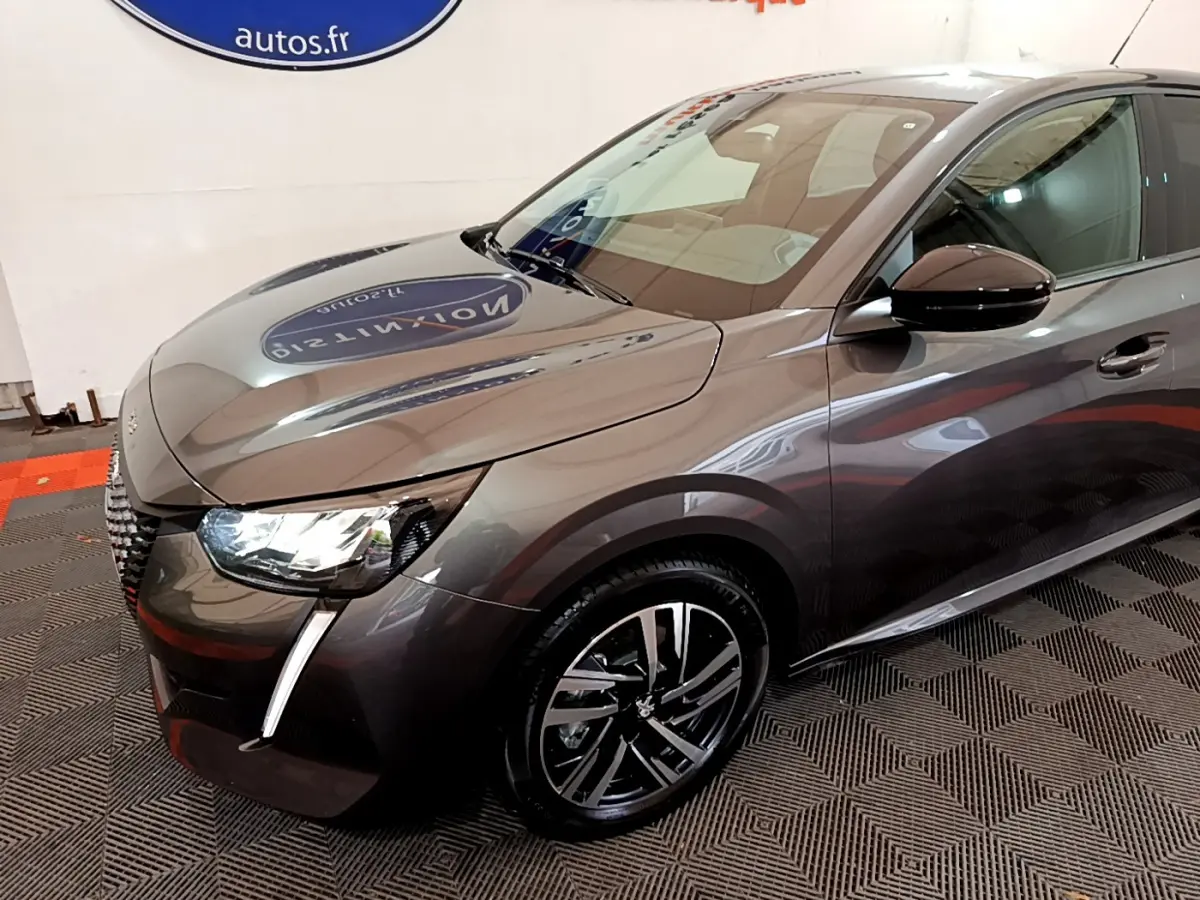 PEUGEOT 208 gris foncé en vue 3/4 avant droit, mettant en valeur ses phares LED et jantes alliage modernes.
