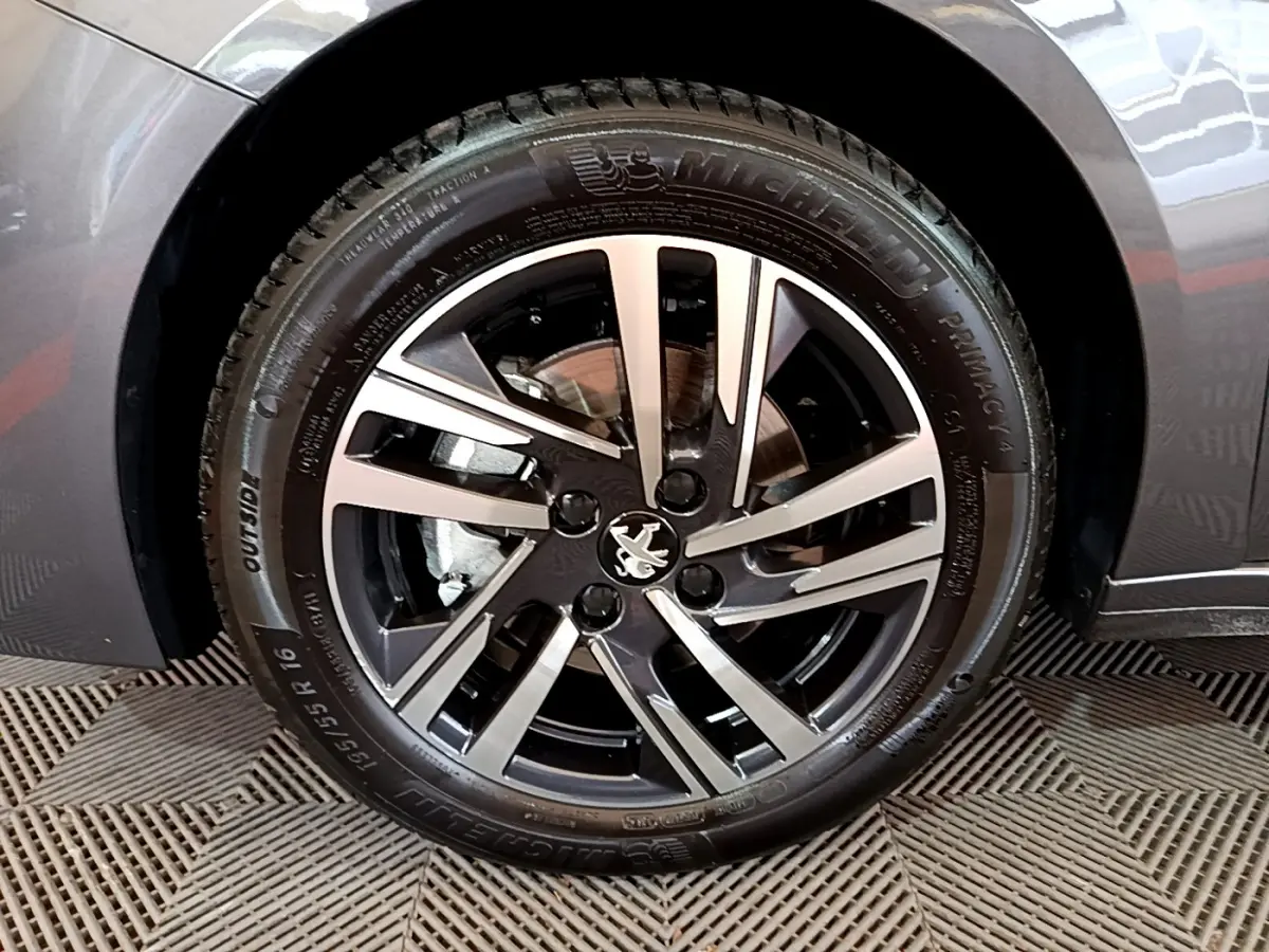 Gros plan sur la roue avant droite gris foncé d'une Peugeot 208 avec jante alliage au design moderne.