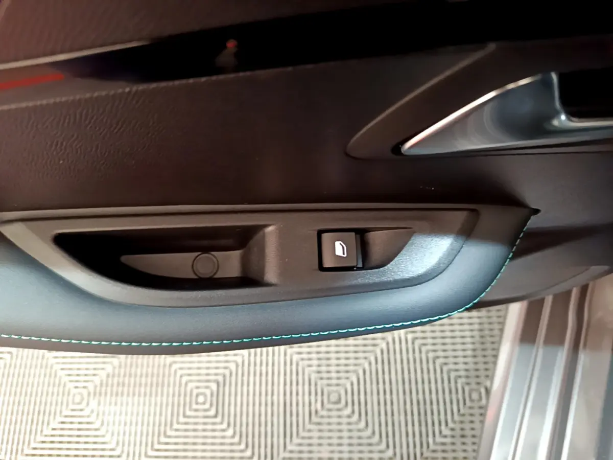 Poignée intérieure de porte côté gauche avec bouton de verrouillage sur Peugeot 208 gris foncé, vue rapprochée.