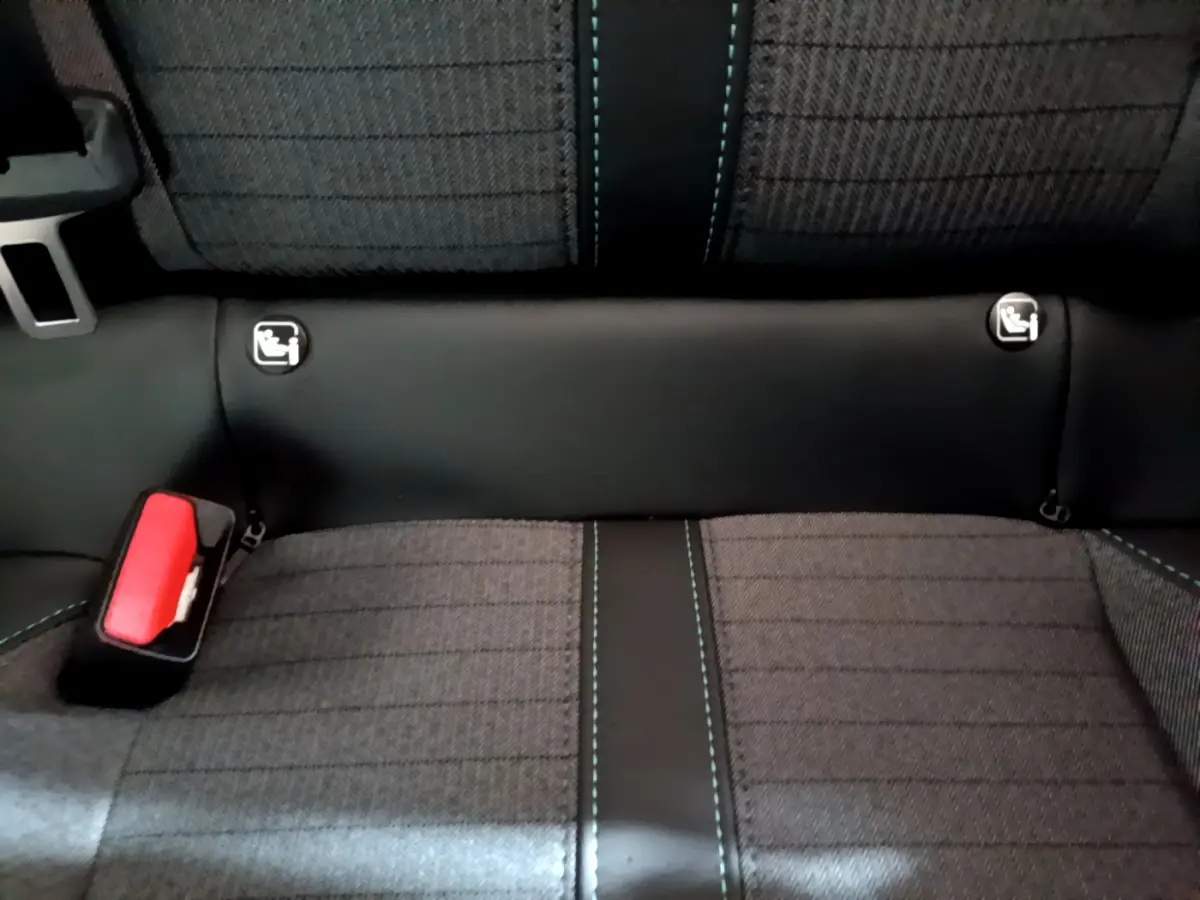 Gros plan sur la banquette arrière gris foncé de la Peugeot 208 avec coutures bleues et fixations Isofix visibles