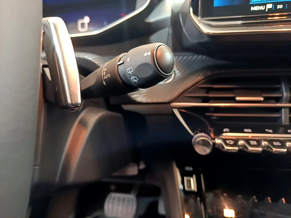 Gros plan sur la commande d'essuie-glace à gauche du volant dans l'habitacle noir de la Peugeot 208 2022.