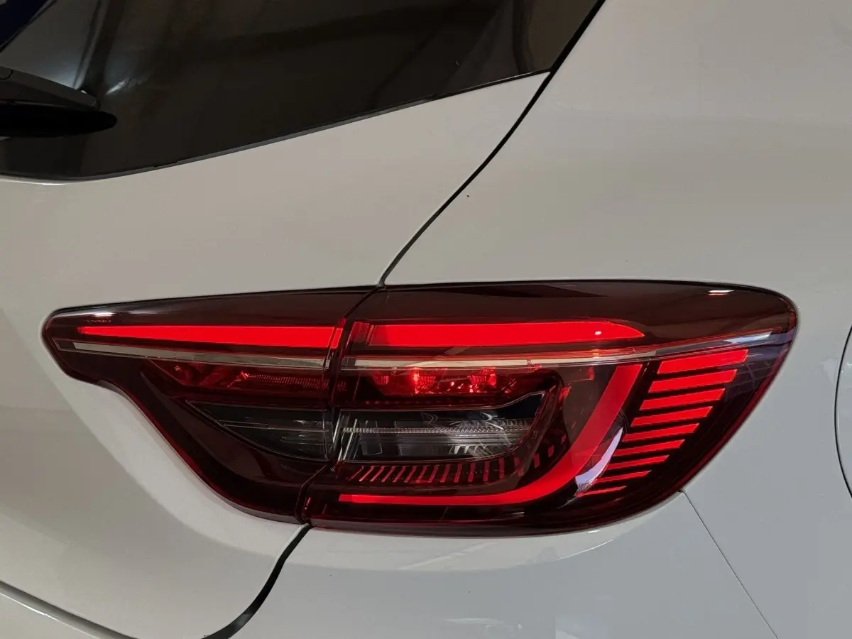 Gros plan sur le feu arrière droit rouge d’une Renault Clio Business blanc nacré, soulignant ses lignes modernes.