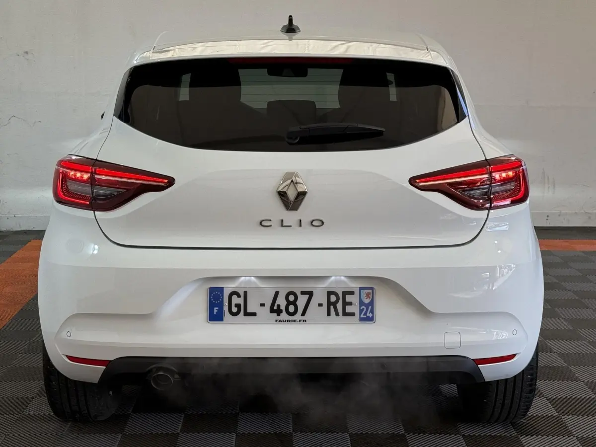 Vue arrière d'une Renault Clio blanche 2023 avec feux LED allumés et plaque d'immatriculation française visible.