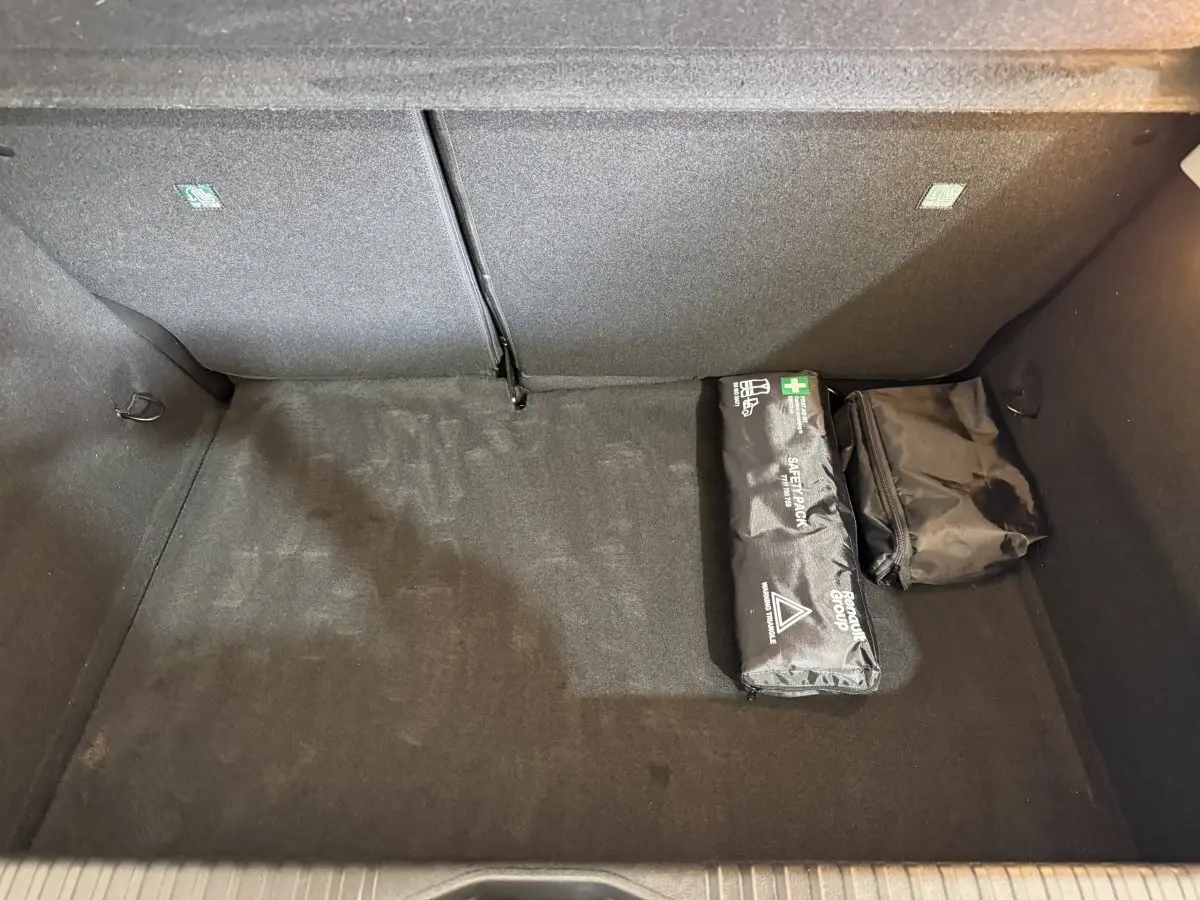 Coffre noir de Renault Clio Business blanc, vue plongeante montrant un kit de sécurité et un sac de rangement.