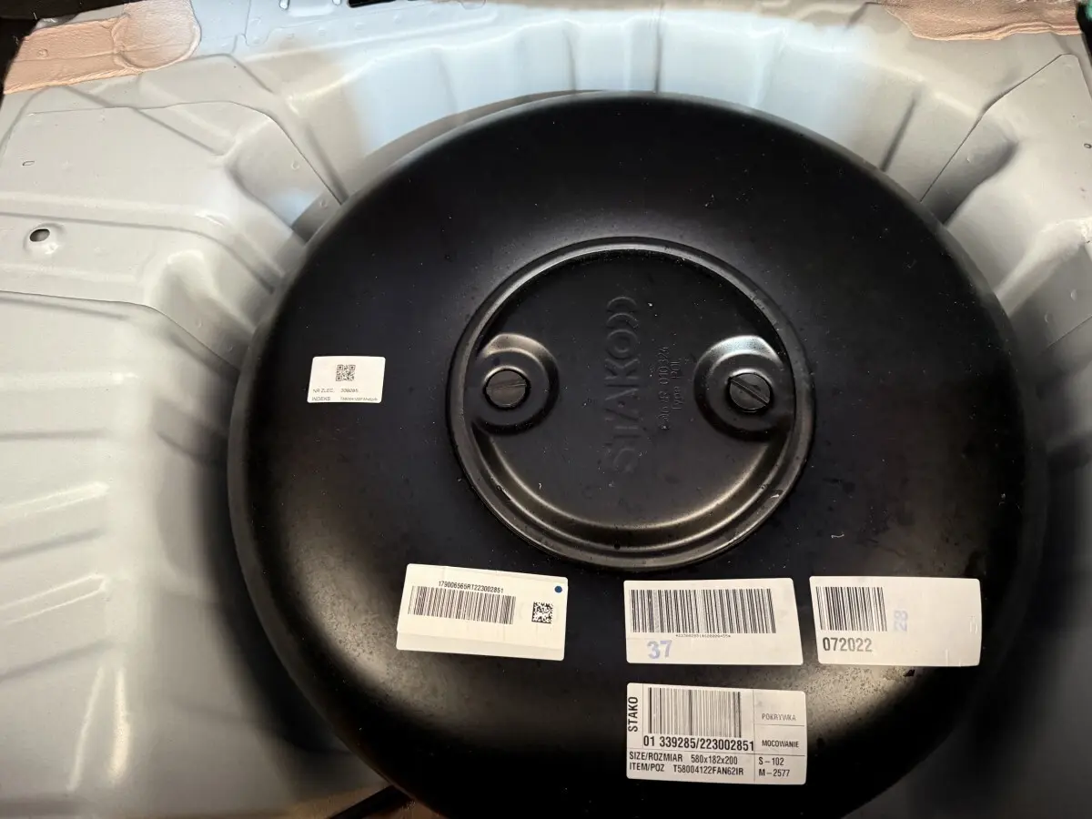 Vue rapprochée du réservoir GPL noir dans le coffre blanc d'une Renault Clio Business TCe 100 GPL 2023.