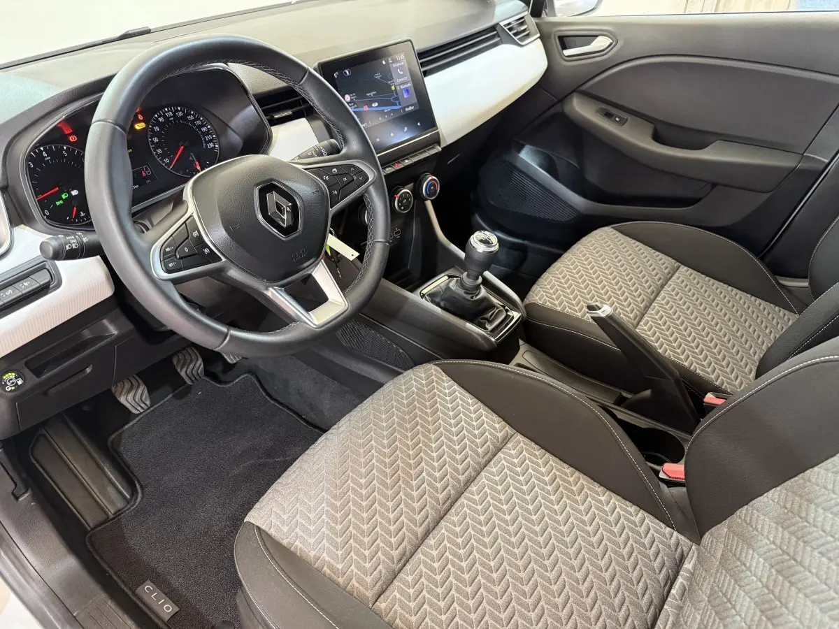 Intérieur avant droit de la Renault Clio Business TCe 100 GPL 2023, volant cuir, sièges tissu gris et console centrale manuelle.