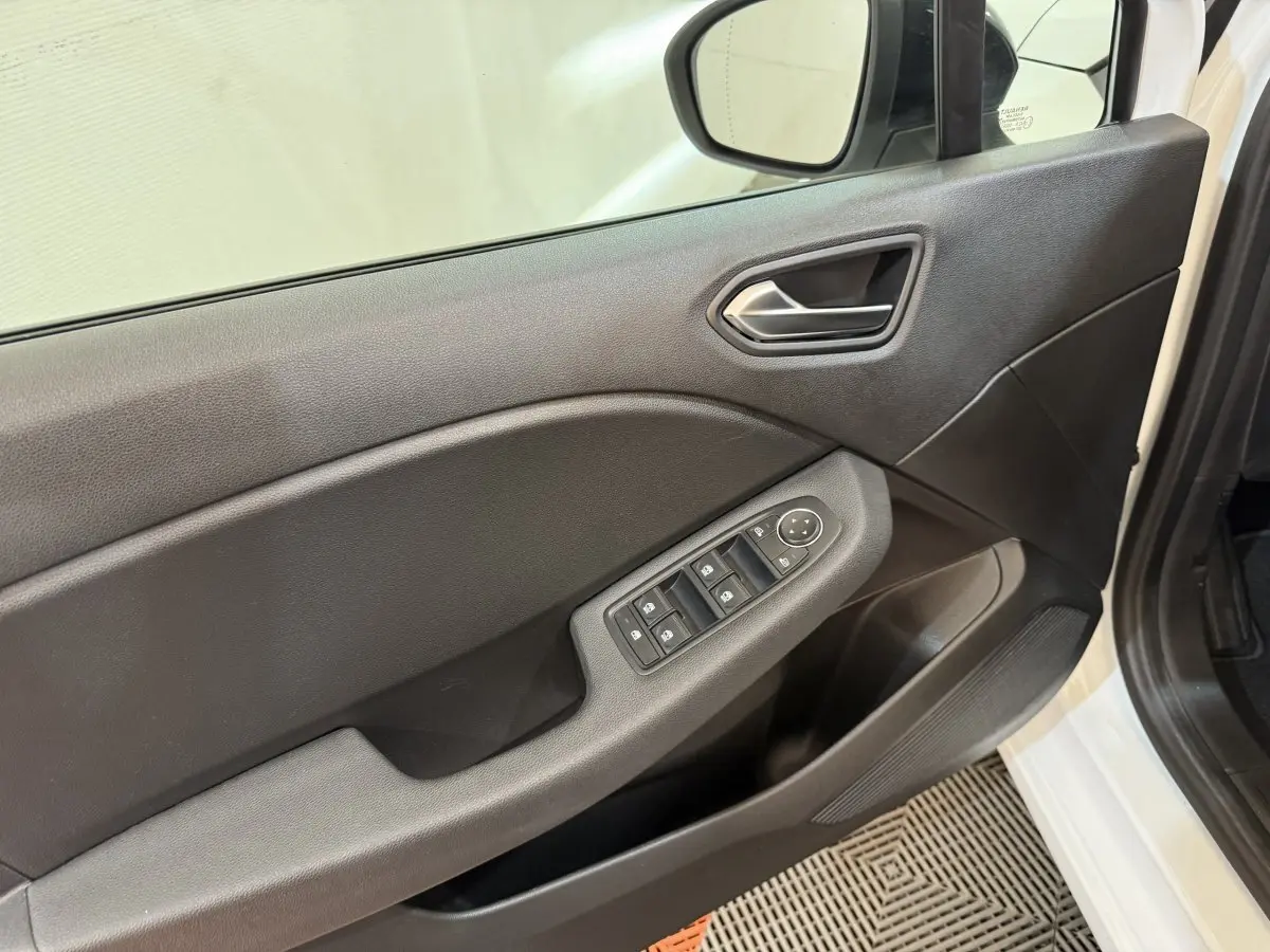 Vue rapprochée de la porte avant gauche blanche d’une Renault Clio 2023 avec commandes électriques des vitres et rétroviseur.