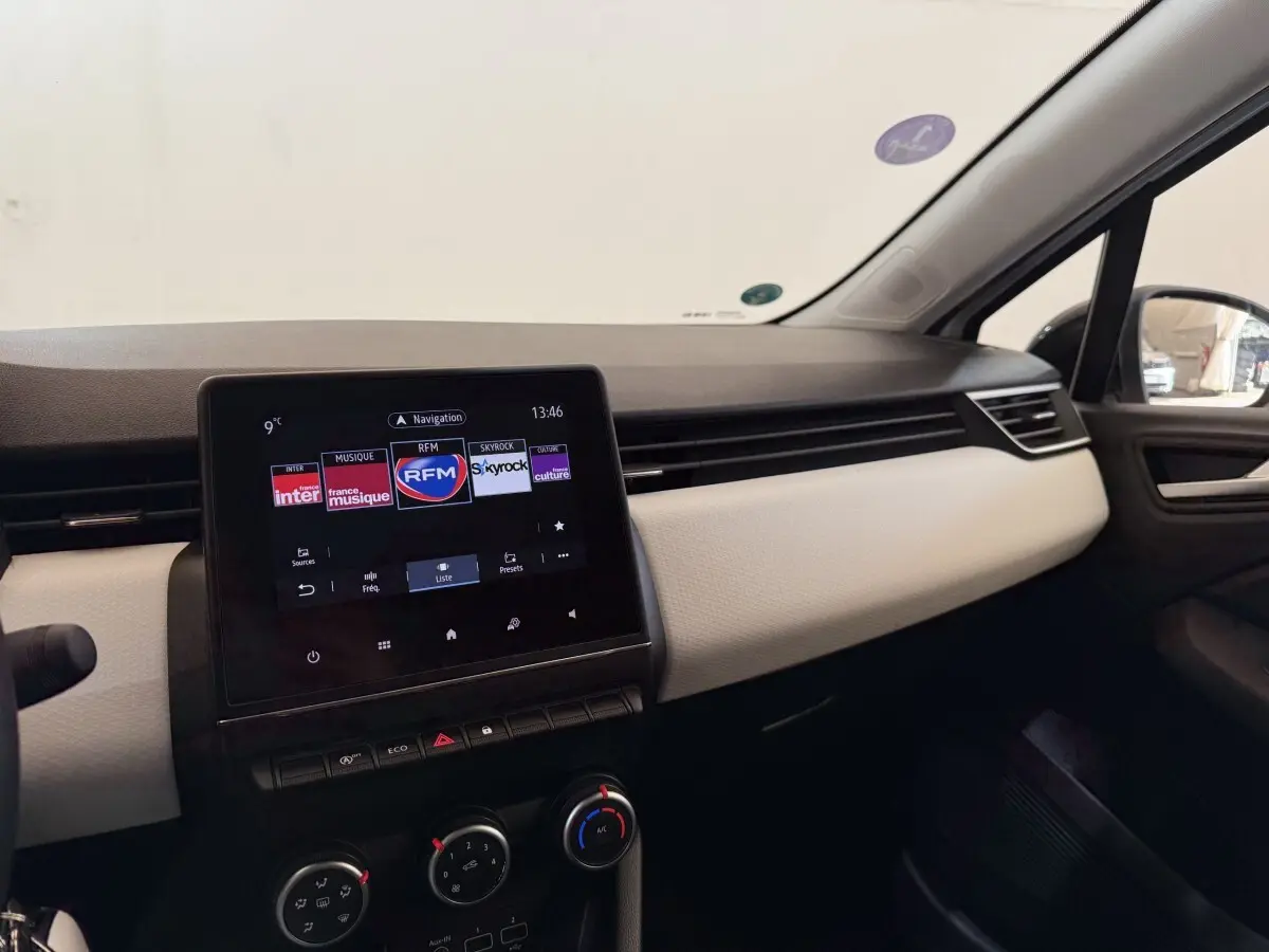 Tableau de bord de Renault Clio Business blanc, vue intérieure côté passager avec écran tactile central allumé.