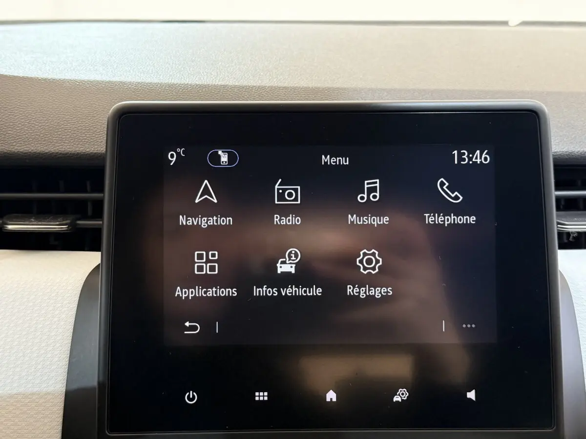 Écran tactile central de la Renault Clio Business blanc, affichant le menu principal avec navigation et radio.