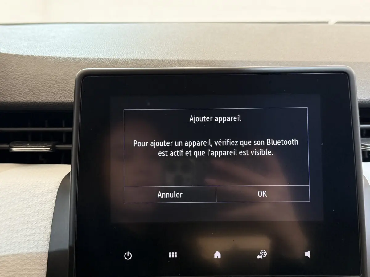 Écran tactile central du tableau de bord de la Renault Clio Business blanc, affichant un message Bluetooth.
