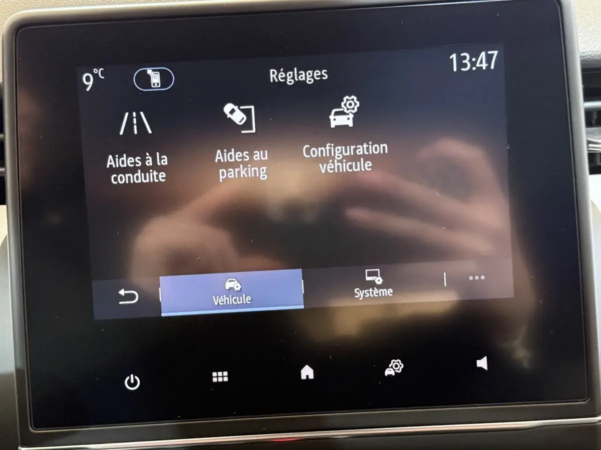 Écran tactile central de la Renault Clio Business blanc montrant le menu des réglages aides à la conduite et parking.