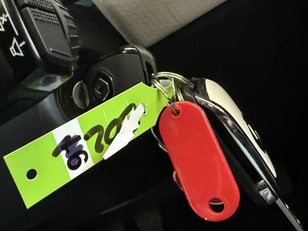 Clé de contact Renault Clio Business TCe 100 GPL 2023 avec porte-clés rouge et étiquette verte, vue intérieure rapprochée.