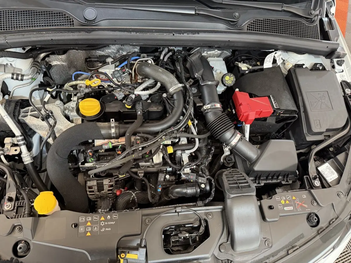 Vue plongeante sur le moteur blanc de la Renault Clio Business TCe 100 GPL 2023 avec bouchons jaunes visibles.