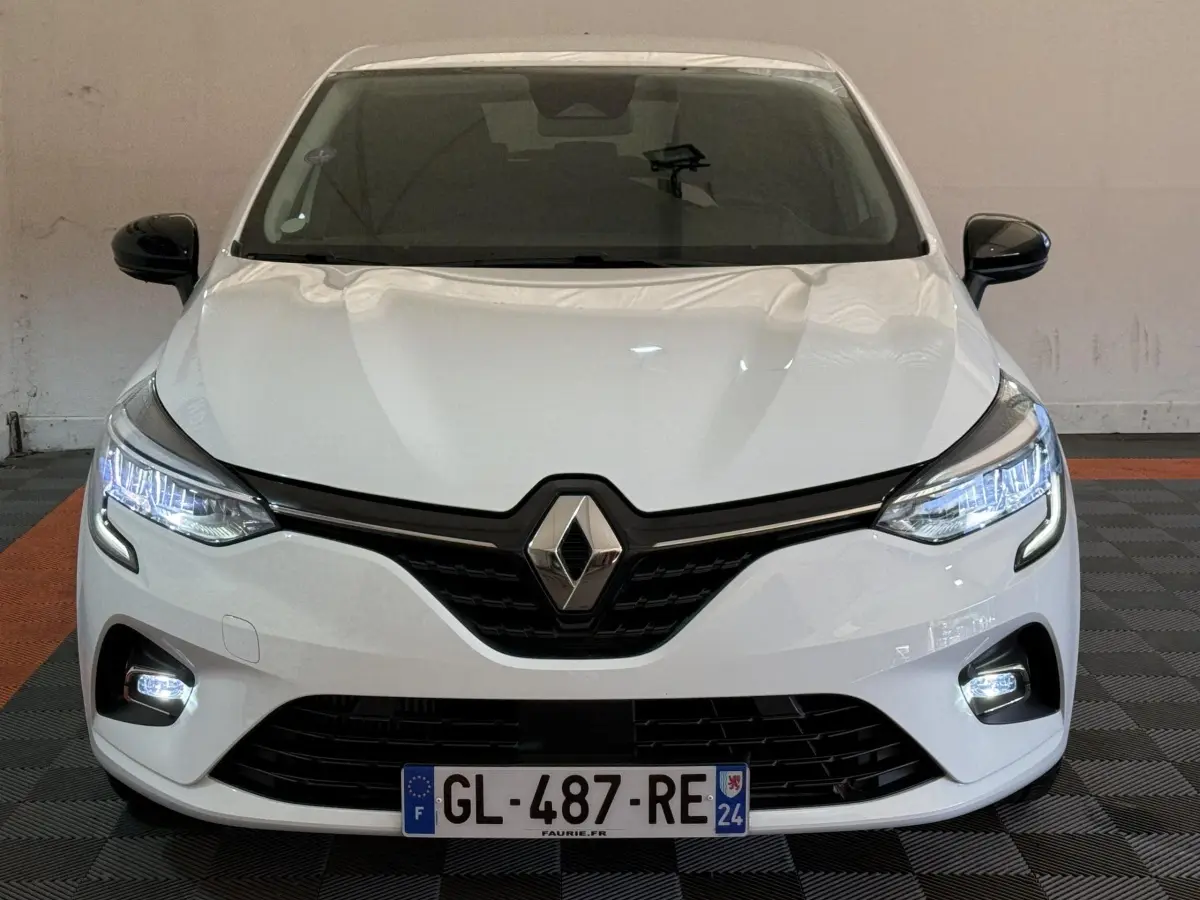 Vue avant d'une Renault Clio Business TCe 100 GPL blanche avec phares LED allumés et calandre noire distinctive.