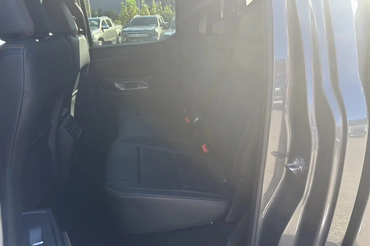 Vue intérieure côté droit sur les sièges arrière en cuir noir avec surpiqûres orange du Ford Ranger gris carbone 2025.