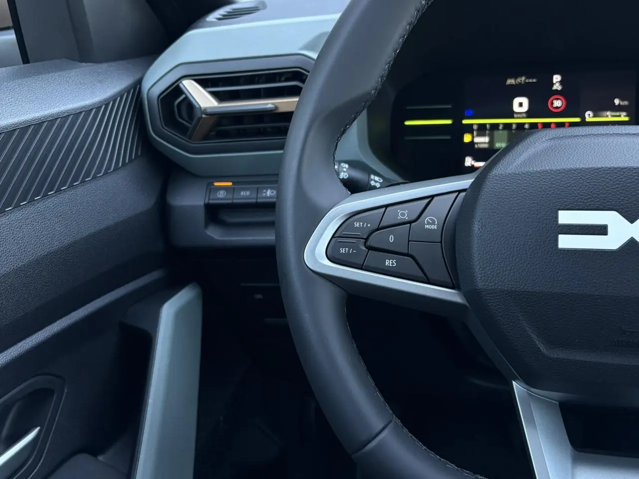 Gros plan sur le volant et le tableau de bord digital du Dacia Duster 2026, intérieur noir avec commandes au volant.