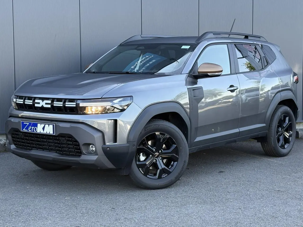 Dacia Duster ECO-G 120 Auto Extrême gris schiste en 3/4 avant droit avec jantes noires et barres de toit.