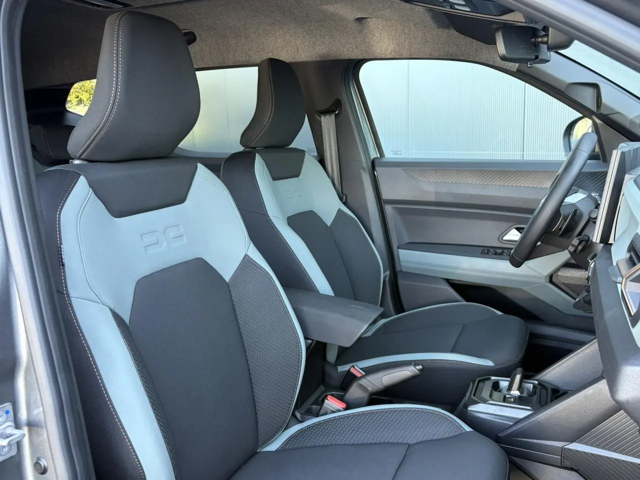 Vue intérieure côté conducteur du Dacia Duster 2026, sièges TEP MicroCloud noirs et gris avec accoudoir central.