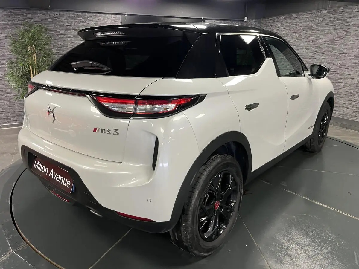 Vue 3/4 arrière droite du DS3 Crossback bi-ton blanc et noir avec jantes noires et becquet de toit noir.
