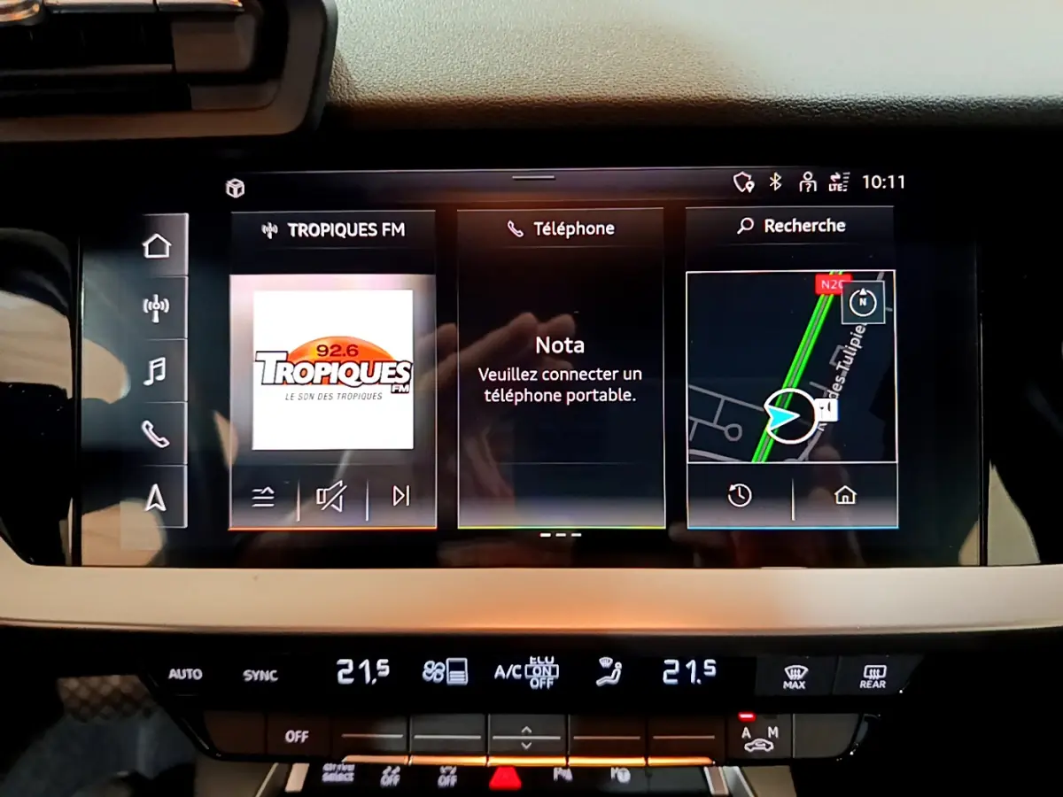 Écran tactile central de l’Audi A3 Business Line 2023 affichant radio, téléphone et navigation, avec commandes climatisation en dessous.