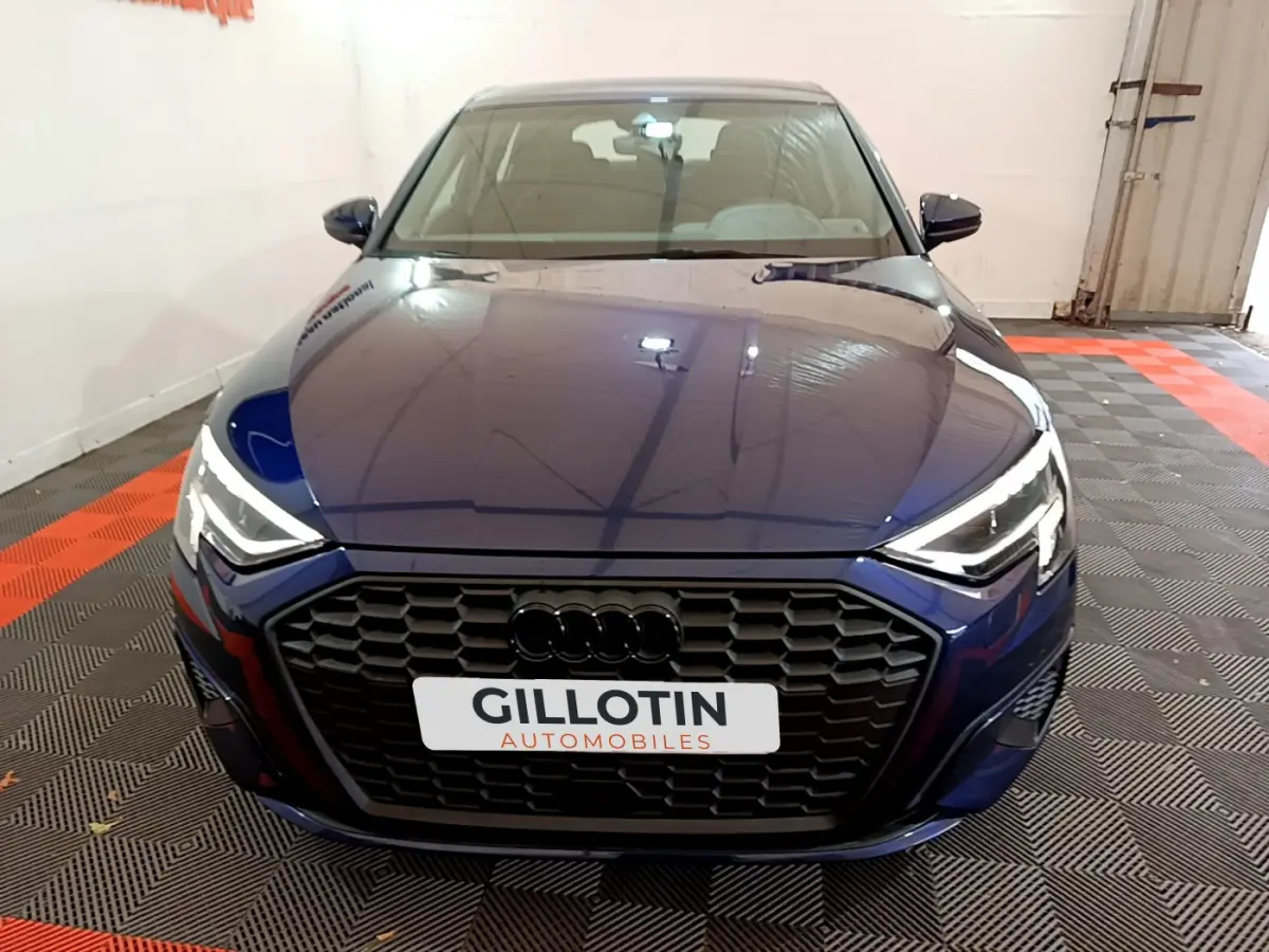 Vue avant d'une Audi A3 35 TFSI bleu profond avec calandre noire et phares LED allumés en intérieur
