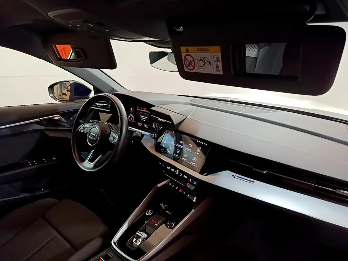 Intérieur de l'Audi A3 35 TFSI 2023 vu côté conducteur, tableau de bord moderne avec écrans tactiles et volant cuir.
