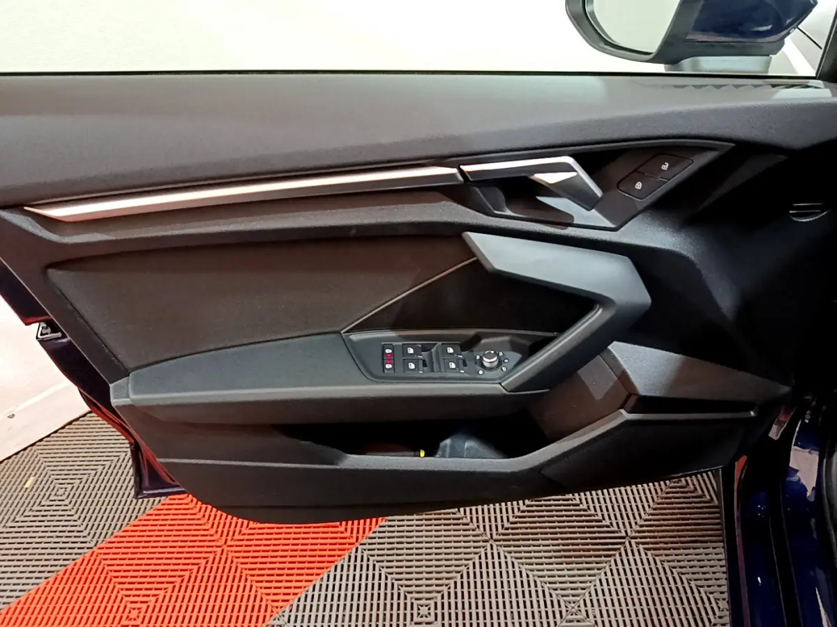 Porte avant gauche ouverte de l'Audi A3 35 TFSI bleu 2023, avec commandes des vitres et verrouillage visibles.