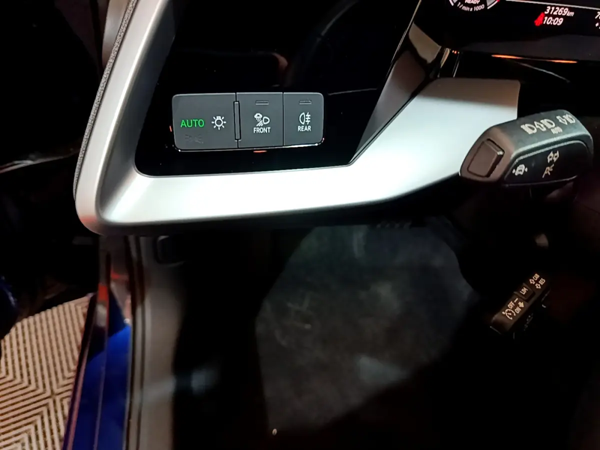 Détail du tableau de bord argenté avec commandes d'éclairage et leviers de fonction dans l'Audi A3 bleu 2023.