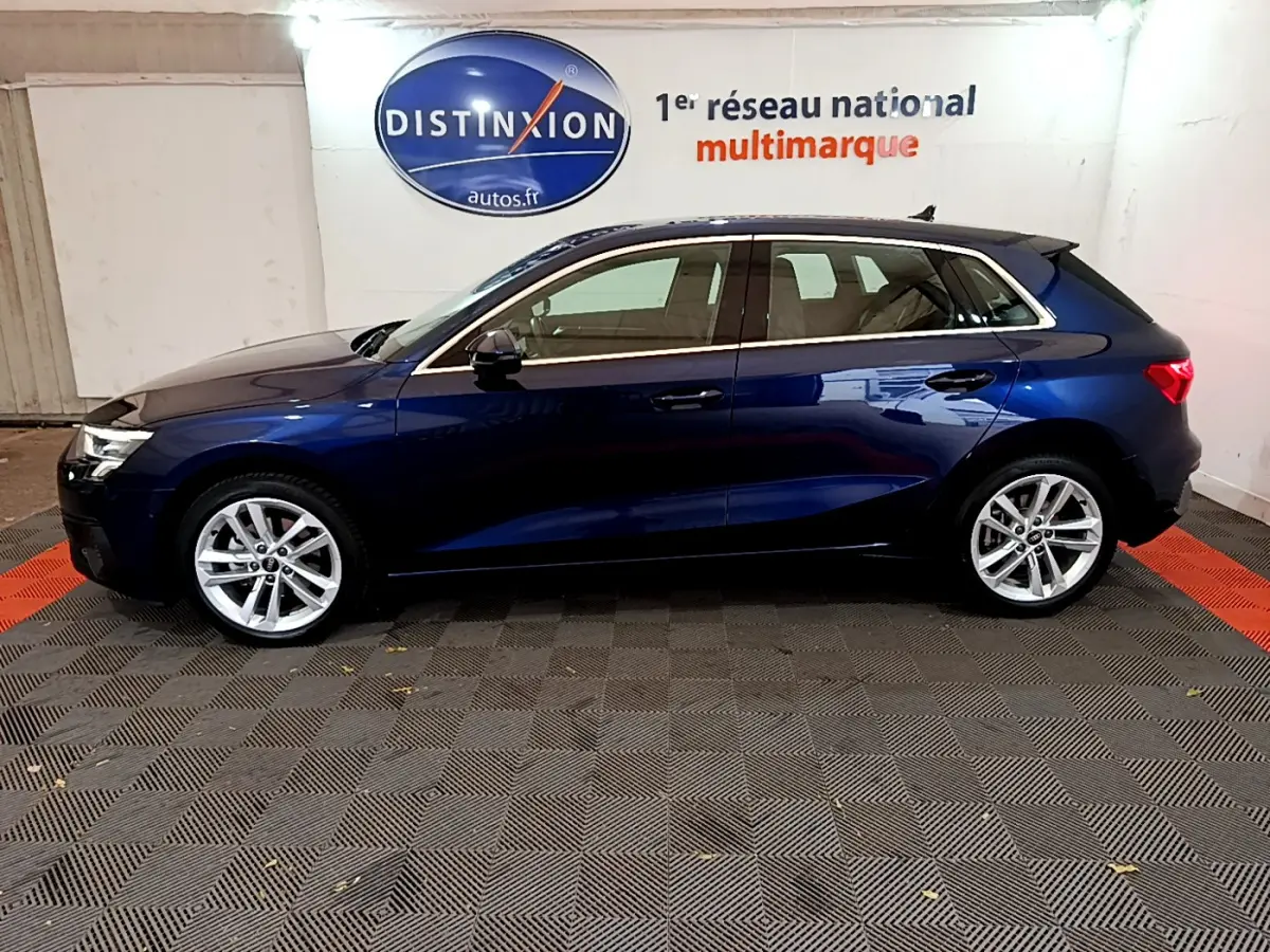 Profil côté gauche d'une Audi A3 bleu foncé 2023 garée en intérieur avec jantes alliage et vitres teintées.