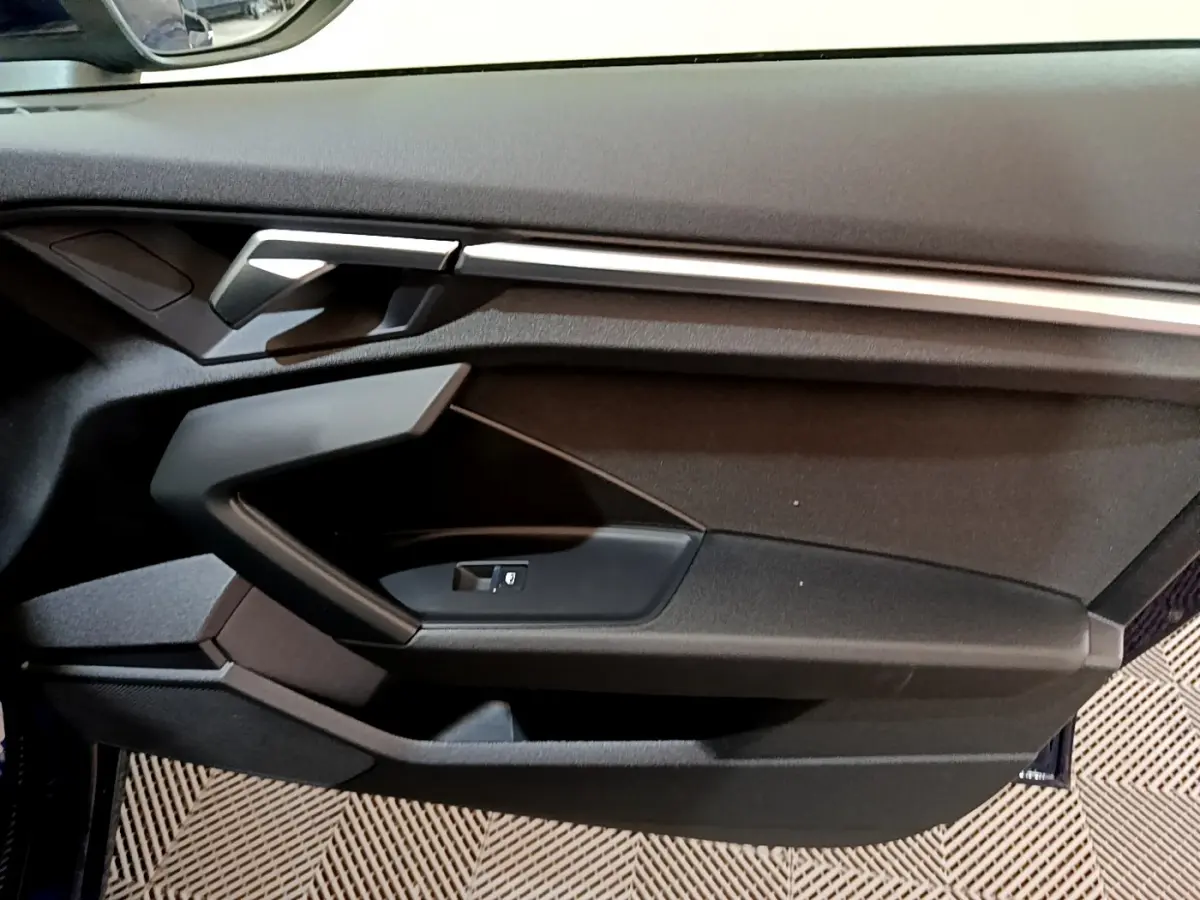 Vue rapprochée de la porte côté gauche de l'Audi A3 Business Line 2023, avec garniture noire et insert argenté.