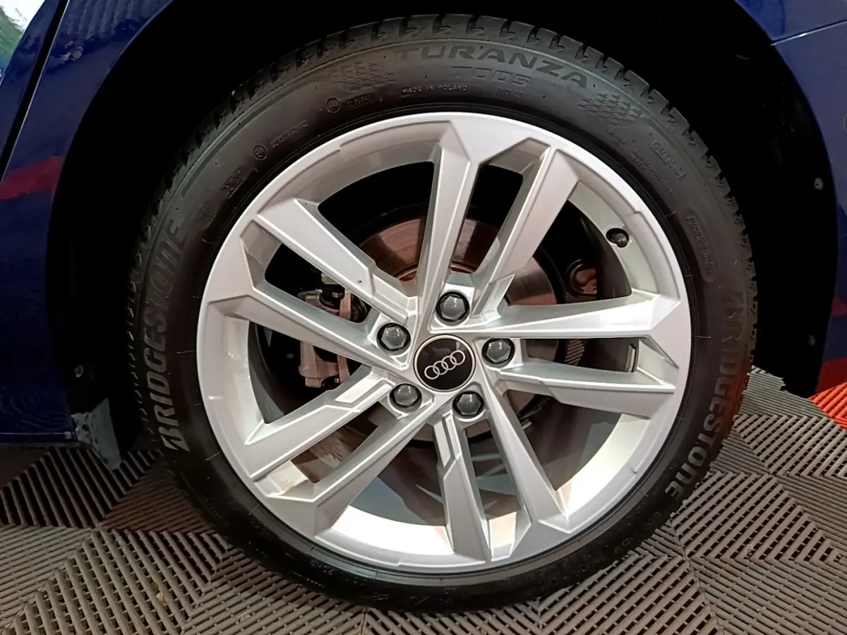 Gros plan sur la jante alliage argentée avec logo Audi d'une A3 bleu 35 TFSI 150 MHEV S Tronic Business Line 2023