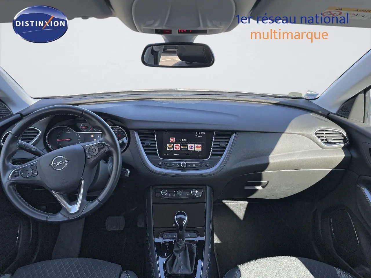 Intérieur de l'Opel Grandland X 2021 vu de face, tableau de bord noir avec écran central et volant multifonction.