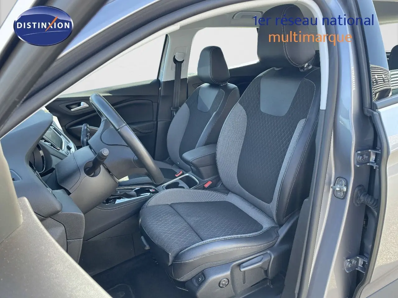 Intérieur avant droit de l'Opel Grandland X gris quartz, sièges tissu et cuir noir avec volant et console visibles.