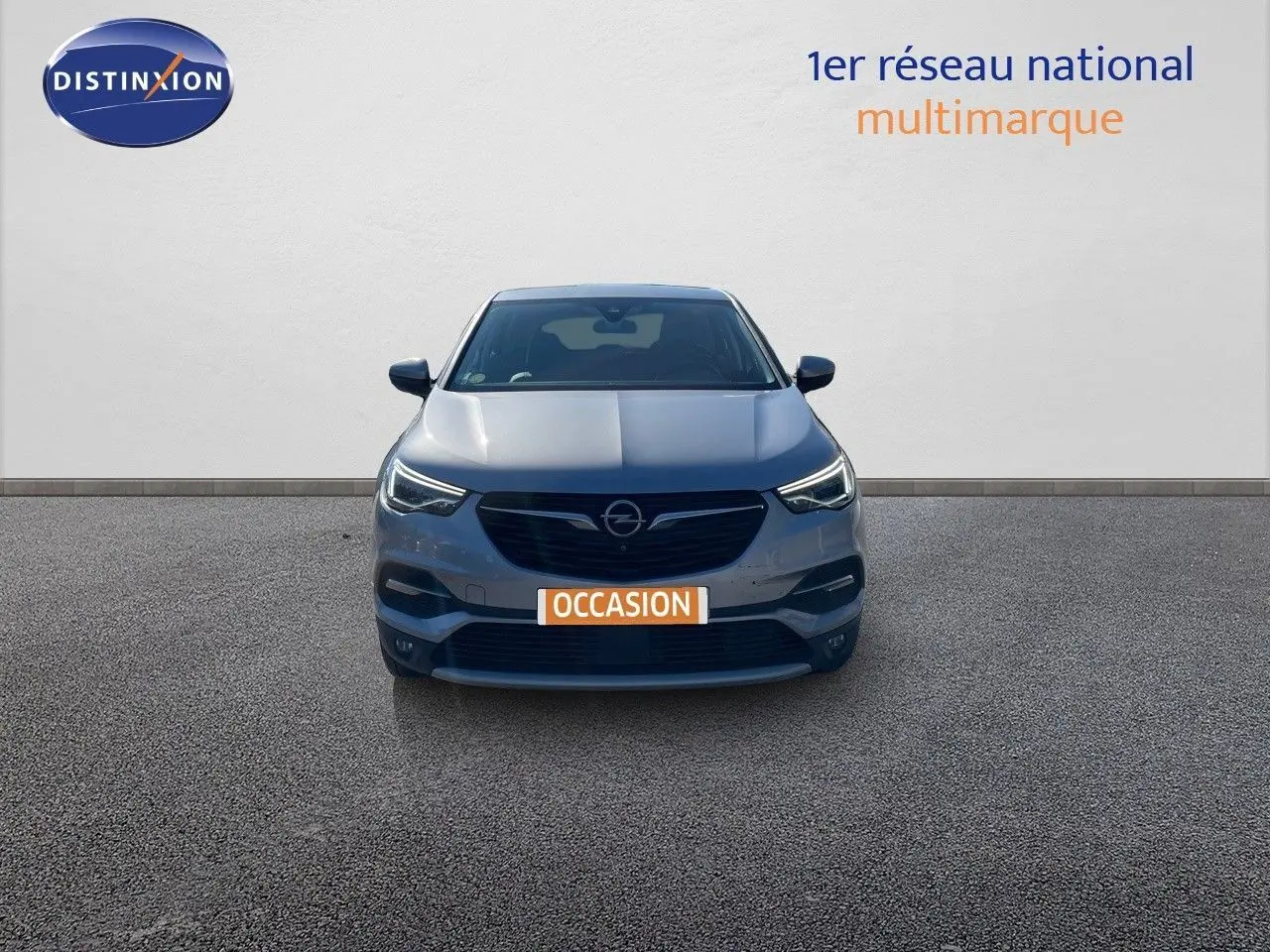 Vue de face d'un Opel Grandland X gris quartz métal avec phares allumés sur fond neutre.