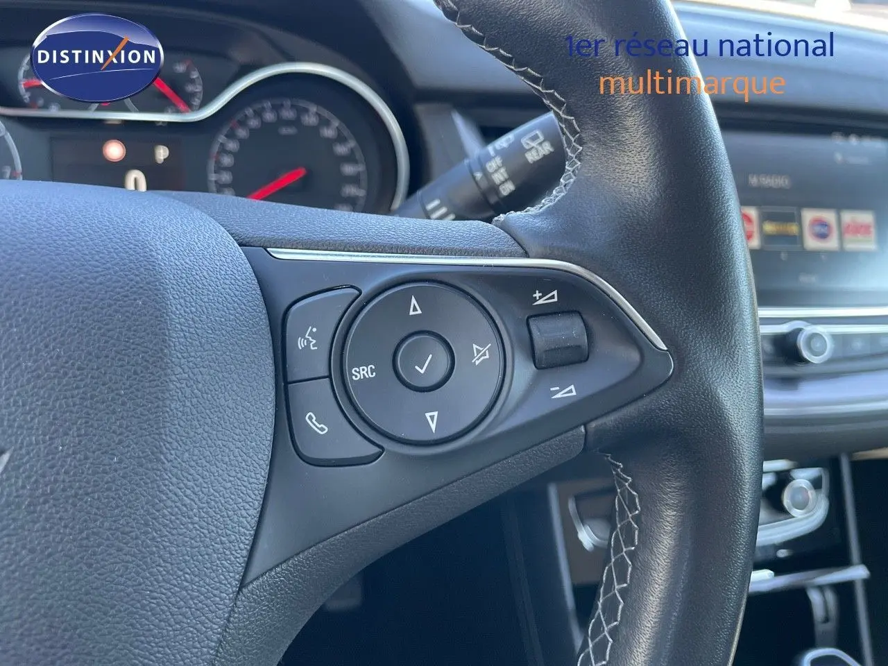 Gros plan sur les commandes au volant en cuir noir de l'Opel Grandland X 2021, avec tableau de bord et écran tactile en arrière-plan.