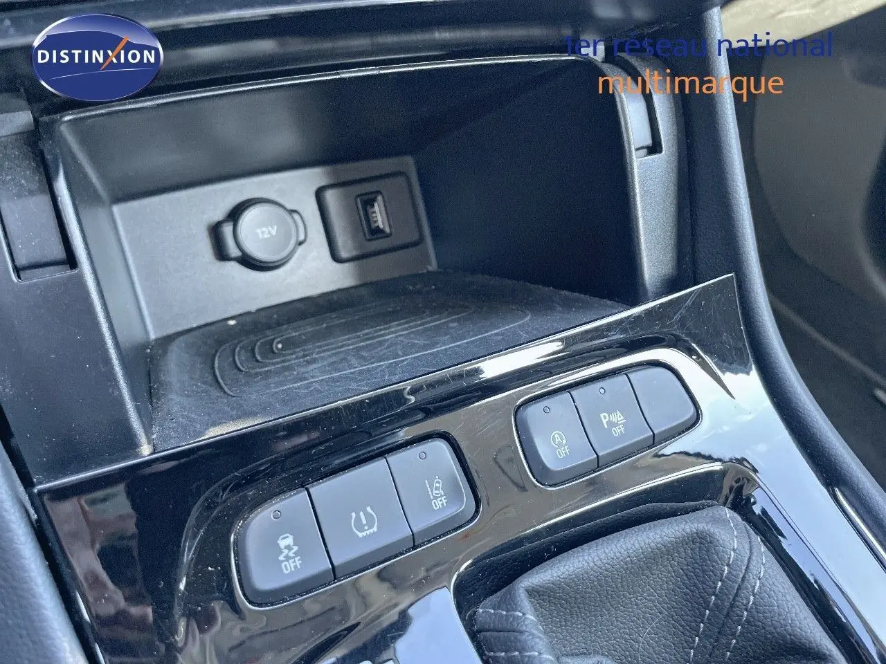 Gros plan sur la console centrale noire de l’Opel Grandland X gris quartz, montrant les boutons de contrôle et prise 12V.