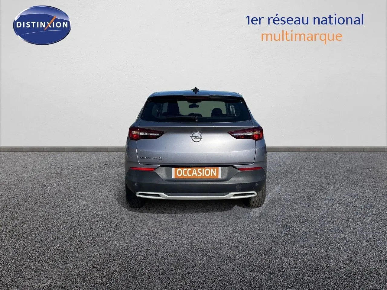 Vue arrière d'un Opel Grandland X gris quartz métal avec plaque "OCCASION" sur fond neutre.