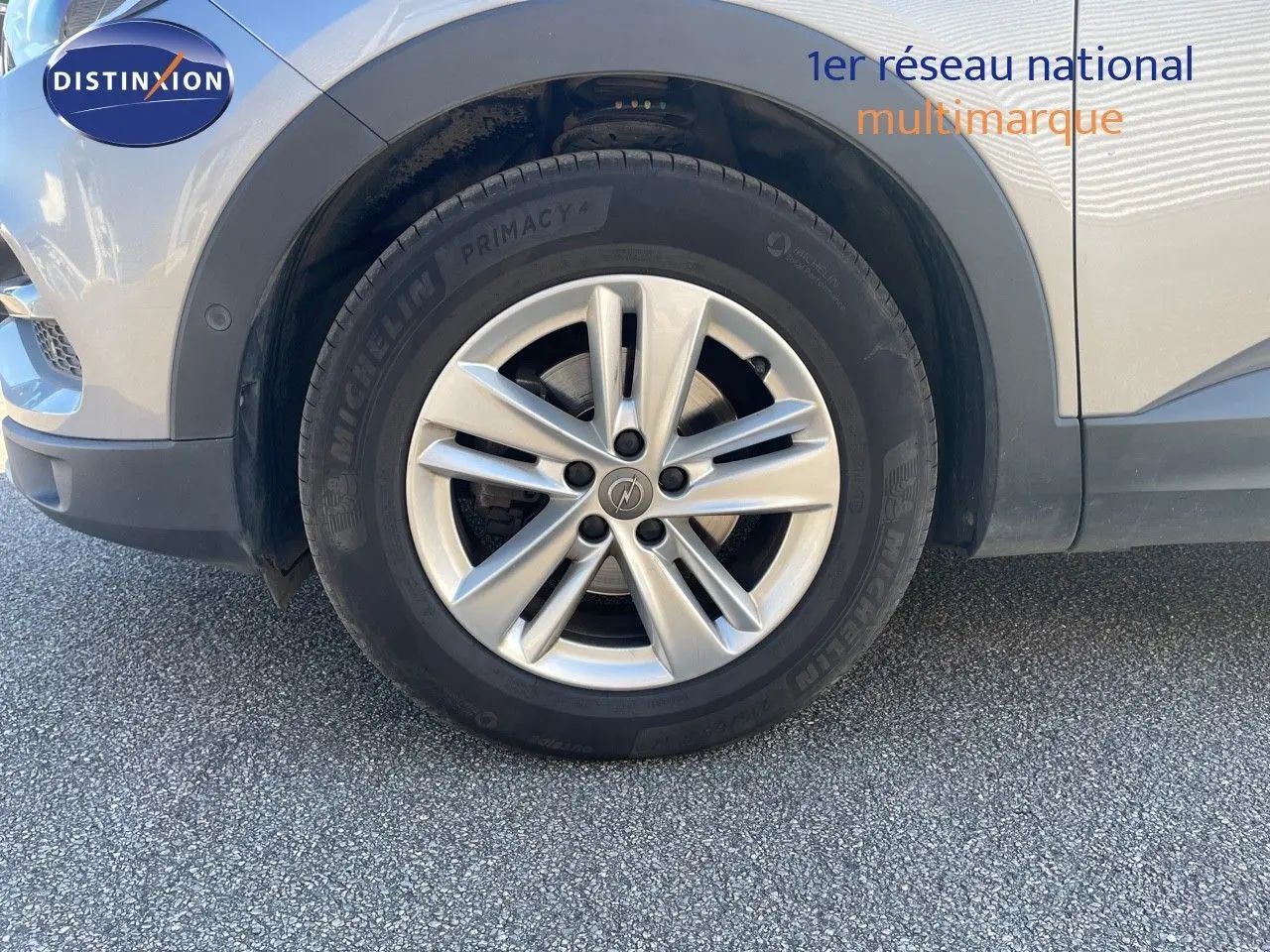 Gros plan sur la roue avant gauche avec jante argentée du SUV Opel Grandland X gris quartz metal.