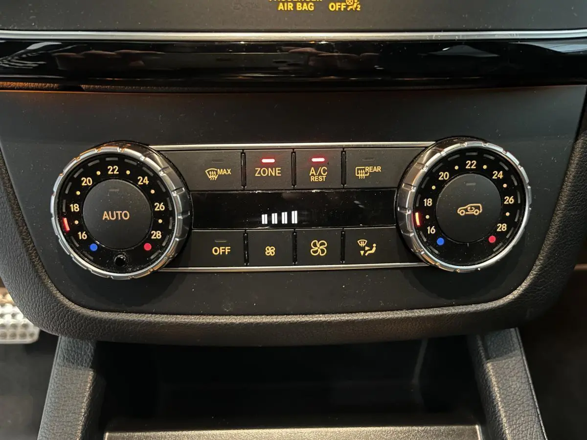 Gros plan sur la commande de climatisation bi-zone du Mercedes GLE Coupé blanc, avec réglages de température et ventilation.