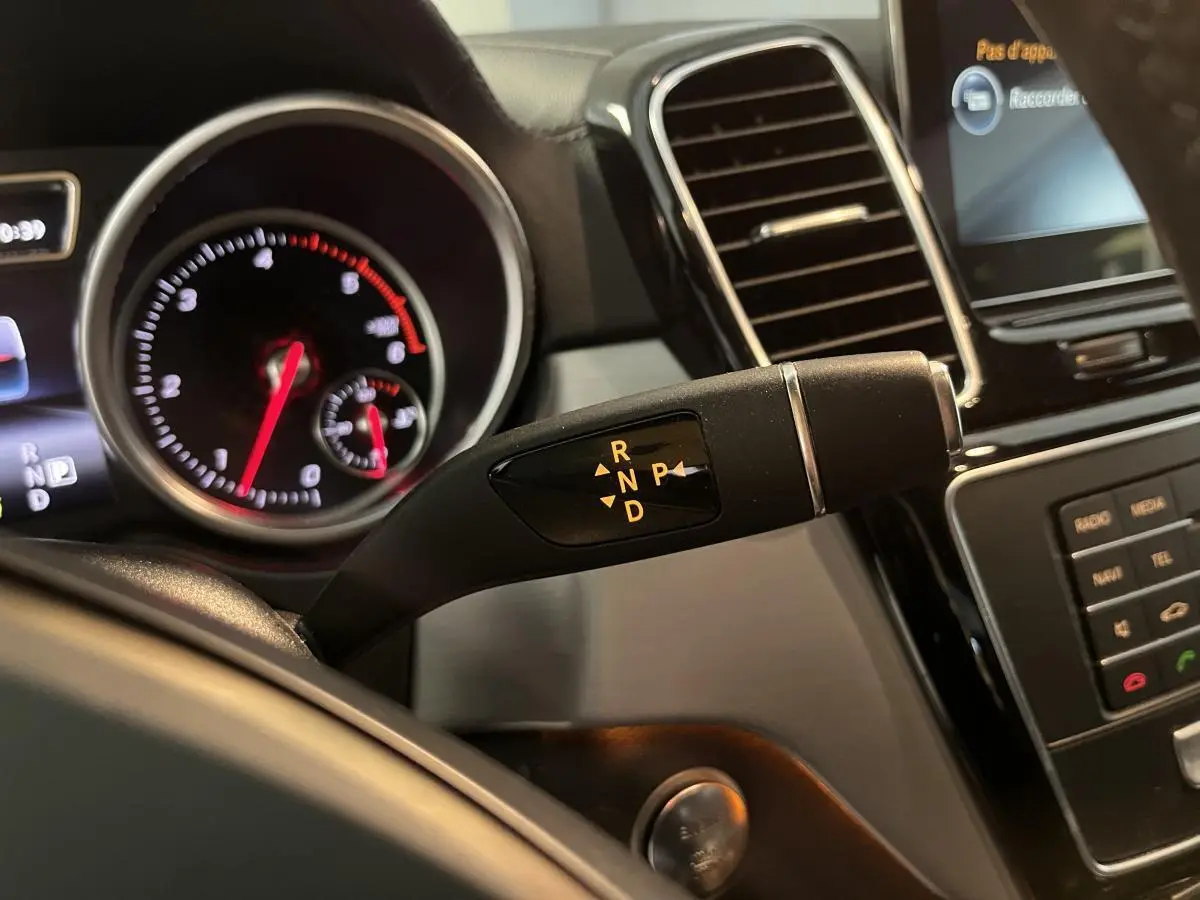 Gros plan sur levier de boîte automatique et tableau de bord noir d'un Mercedes GLE Coupé blanc 2016.