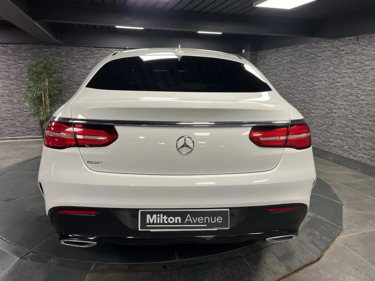 Vue arrière d'un Mercedes GLE Coupé blanc avec feux rouges et double sortie d'échappement chromée.