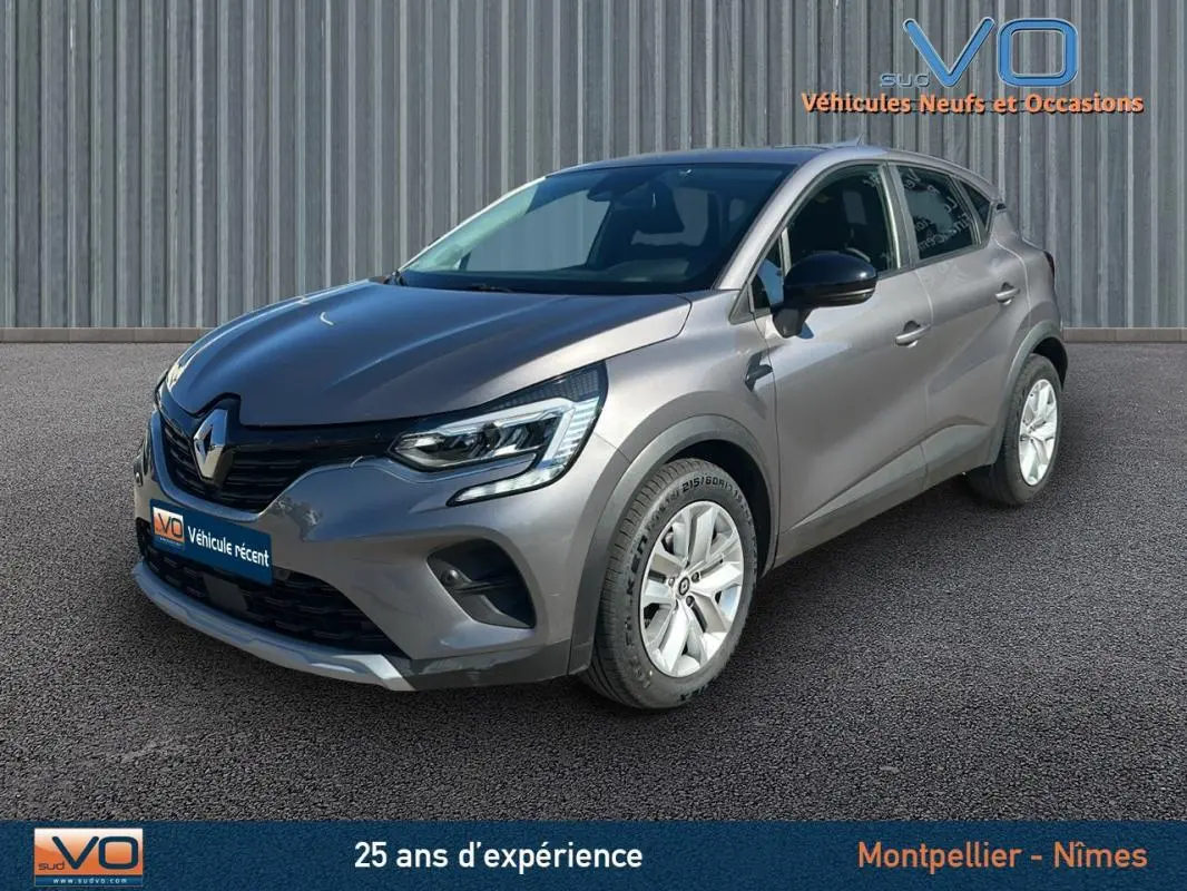 Renault Captur TCe 90 Business gris vu en 3/4 avant droit sur fond neutre avec jantes blanches.