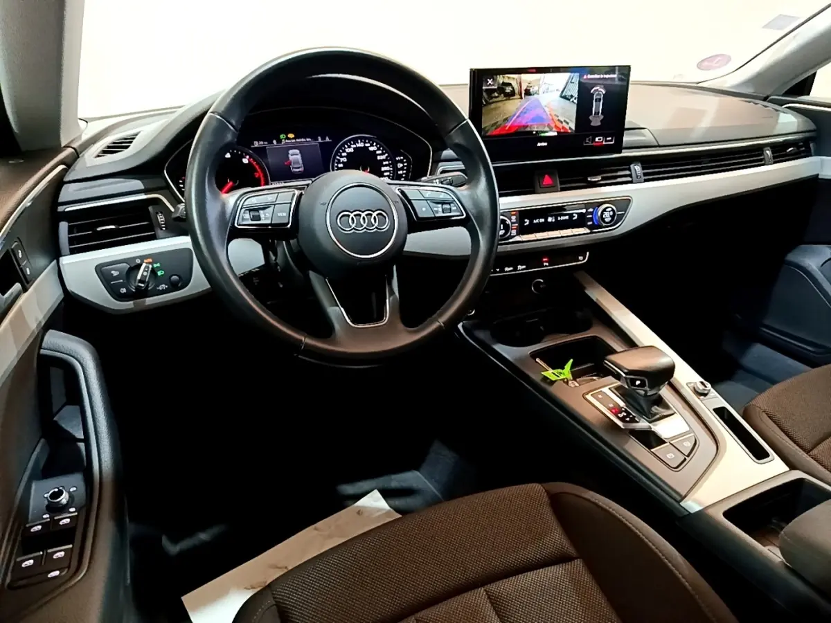 Vue intérieure de l'Audi A5 2021, tableau de bord et volant cuir noir avec écran central affichant la caméra de recul.