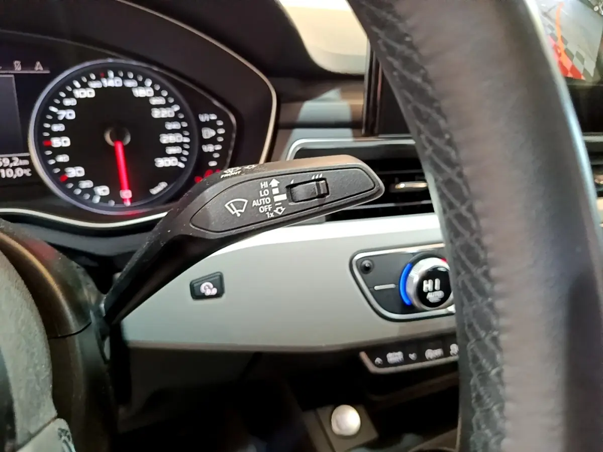 Gros plan sur la manette d’essuie-glace et le tableau de bord gris clair de l’Audi A5 noire, avec volant en cuir visible.