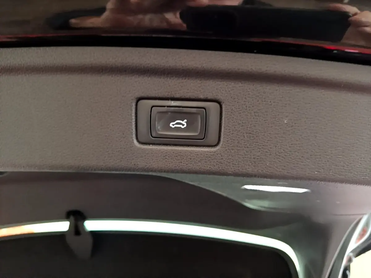 Bouton d'ouverture électrique du coffre vu en gros plan à l'intérieur du hayon d'une Audi A5 noire 2021.