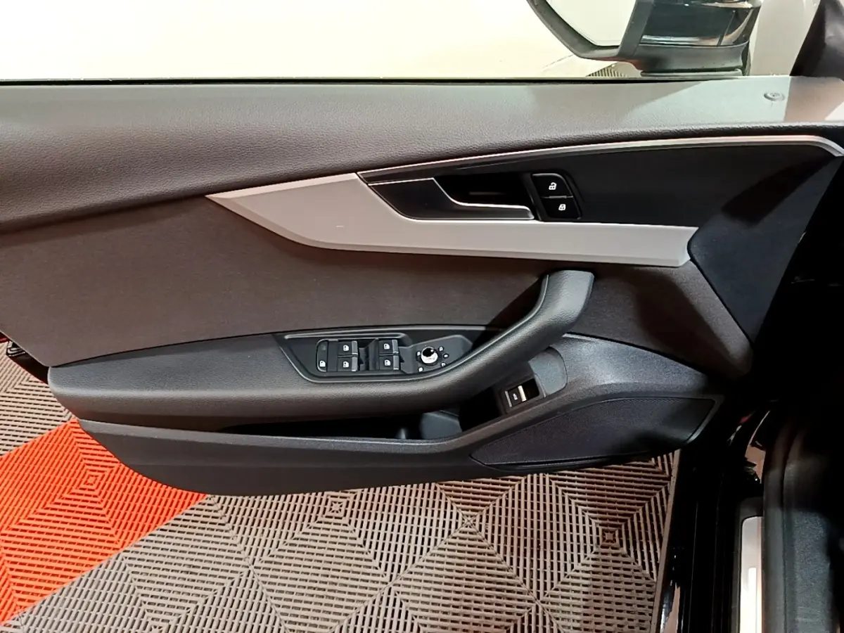 Vue rapprochée de la porte côté gauche d'une Audi A5 noire, avec commandes de vitres et verrouillage intégrés.