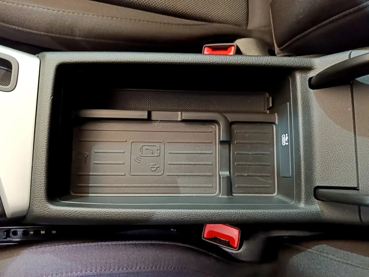 Vue plongeante sur le compartiment central noir de l'Audi A5 35 TFSI 2021, avec indication de charge sans fil et ceintures rouges.