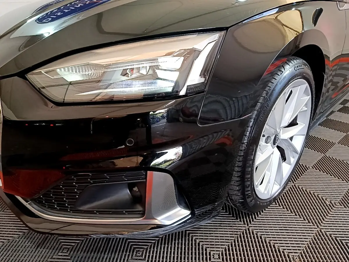 Gros plan sur l'avant droit noir d'une Audi A5 35 TFSI, mettant en valeur le phare LED et la jante alu.